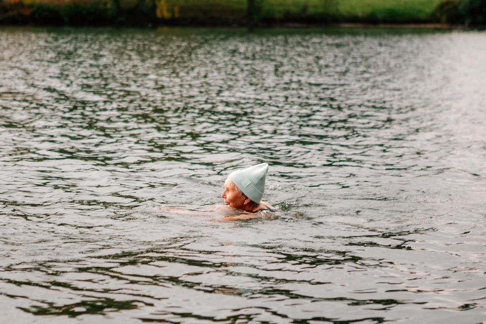 Ältere Frau schwimmt im See mit Mütze